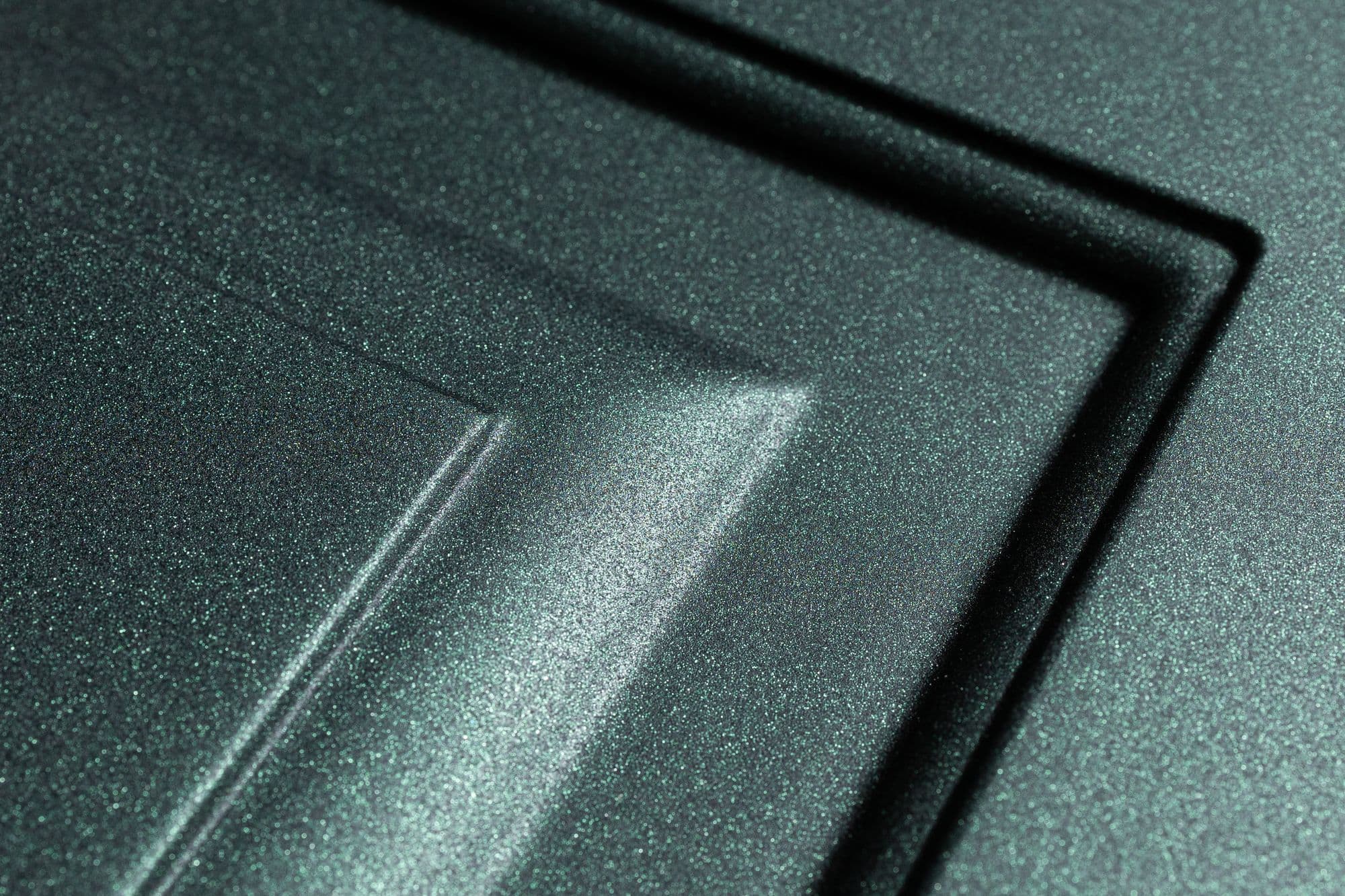 Detalhe de frisos em verde metalizado sob luz lateral